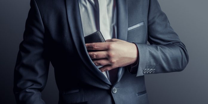 Un hombre saca su billetera del bolsillo, como hará Luckia para pagar por los costos del IVA sobre apuestas.
