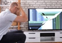 Un hombre se toma la cabeza frente a un televisor roto.