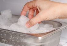 Una mano pone un hielo en el congelador.