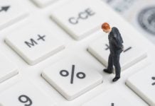 Un hombre miniatura camina sobre una calculadora.