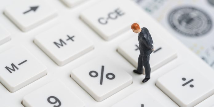 Un hombre miniatura camina sobre una calculadora.