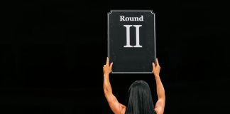 Una mujer alza un cartel de ROUND 2.