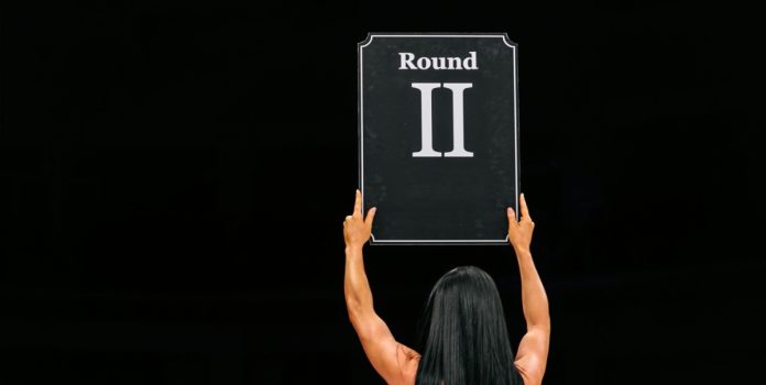 Una mujer alza un cartel de ROUND 2.