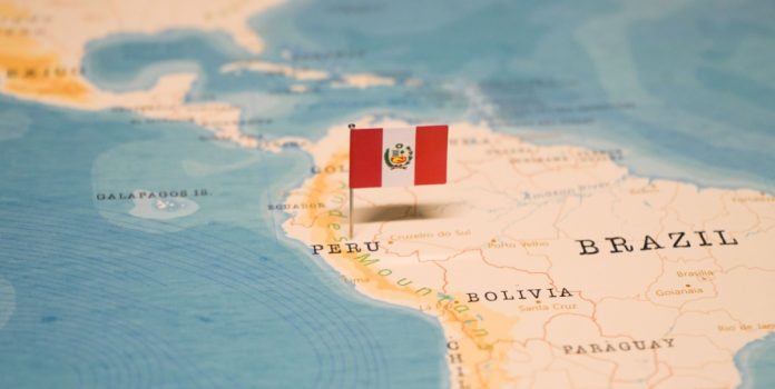 La bandera de Perú clavada sobre el país en un mapa.