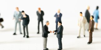 Hombres miniatura se dan la mano.