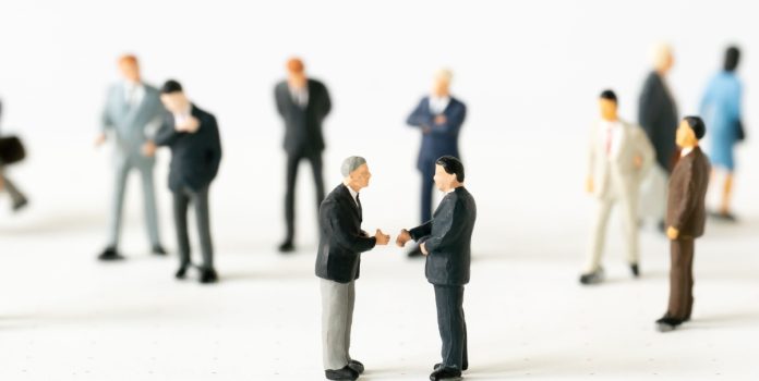 Hombres miniatura se dan la mano.