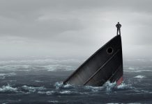 Un hombre de pie sobre la proa de un barco que se hunde en el mar.
