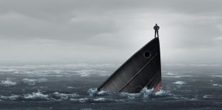 Un hombre de pie sobre la proa de un barco que se hunde en el mar.