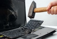 Una persona destruye una computadora portátil con un martillo.
