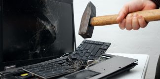 Una persona destruye una computadora portátil con un martillo.