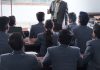 Personas con traje asisten a una clase.