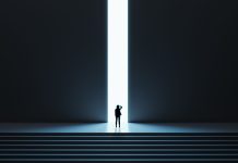 Una mujer avanza sobre una puerta iluminada en la cima de unas escaleras.