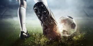 Un futbolista patea una pelota de fútbol.