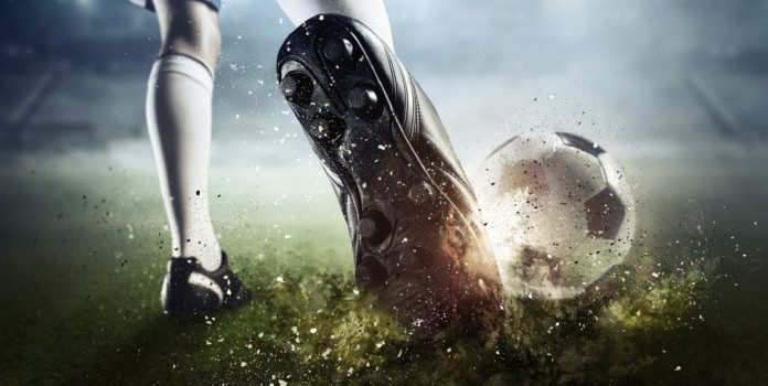 Un futbolista patea una pelota de fútbol.
