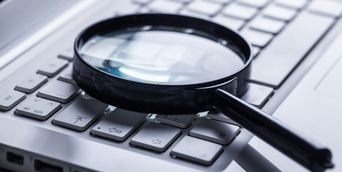 apuestas-br-consumer Una lupa sobre una computadora.