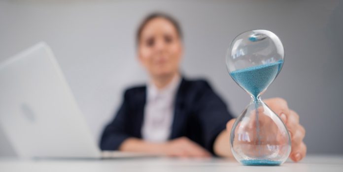 Una mujer da vuelta un reloj de arena.