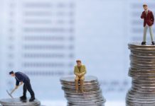 Gente en miniatura, de pie sobre pilas de monedas.