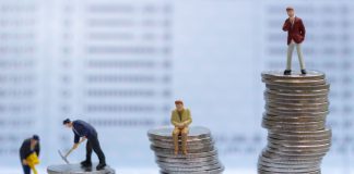 Gente en miniatura, de pie sobre pilas de monedas.