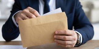 Coljuegos adjudicará la intervención del SUPER Astro por cinco años Un hombre abre un sobre de papel madera.