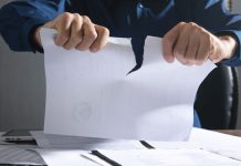 Un hombre rompe una hoja de papel.