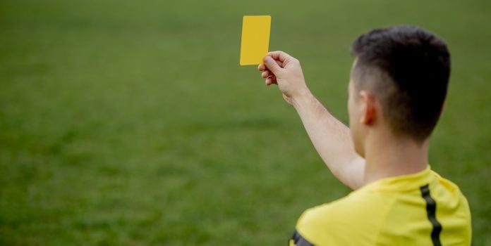 árbitro mostrando tarjeta amarilla
